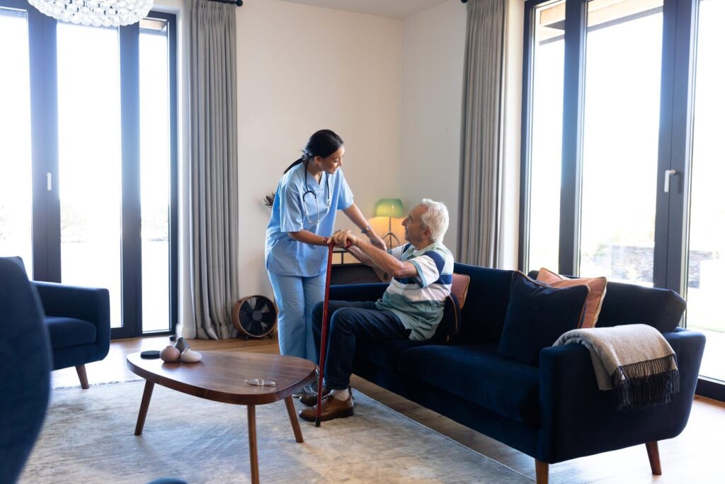 biracial female health worker helping caucasian senior man get up from couch home 13339 334183 biracial female health worker helping caucasian senior man get up from couch home 13339 334183