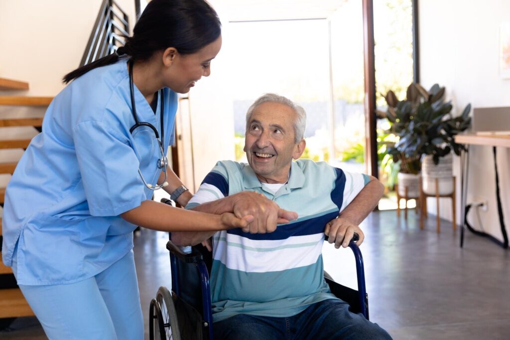 biracial female physiotherapist assisting caucasian senior man getting up from wheelchair home 13339 332752 biracial female physiotherapist assisting caucasian senior man getting up from wheelchair home 13339 332752