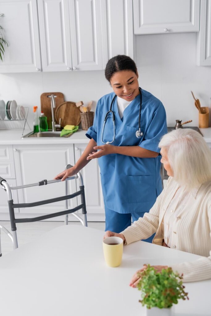 happy multiracial nurse blue uniform pointing with hand walker while standing near senior 1326977 22337