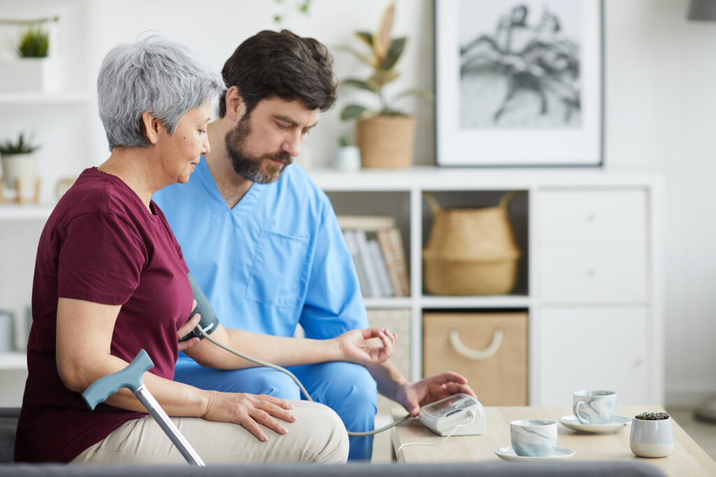 mature male doctor examining blood pressure senior woman while they sitting sofa home mature male doctor examining blood pressure senior woman while they sitting sofa home