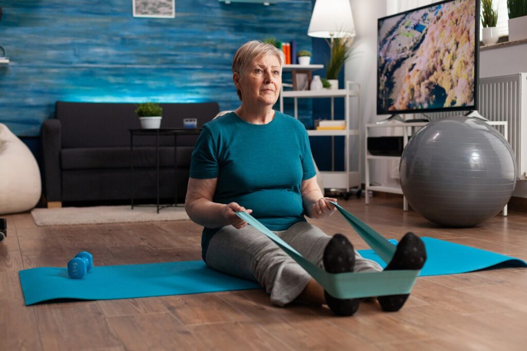 retirement senior woman sitting yoga mat stretching legs muscles using stretch elastic band training body resistance 482257 1633