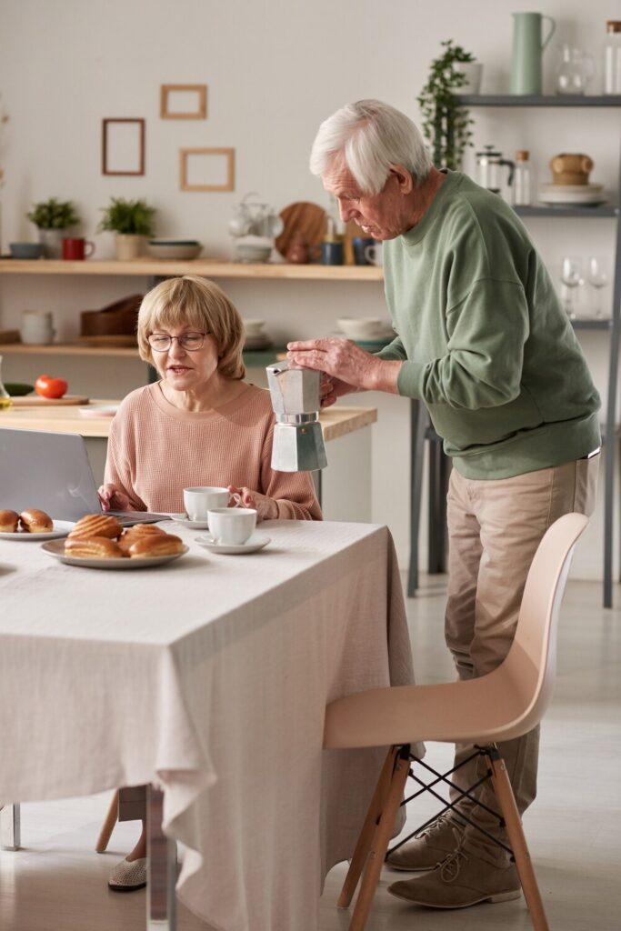 senior man caring his wife pouring hot tea breakfast while she sitting table with laptop 249974 7929 senior man caring his wife pouring hot tea breakfast while she sitting table with laptop 249974 7929